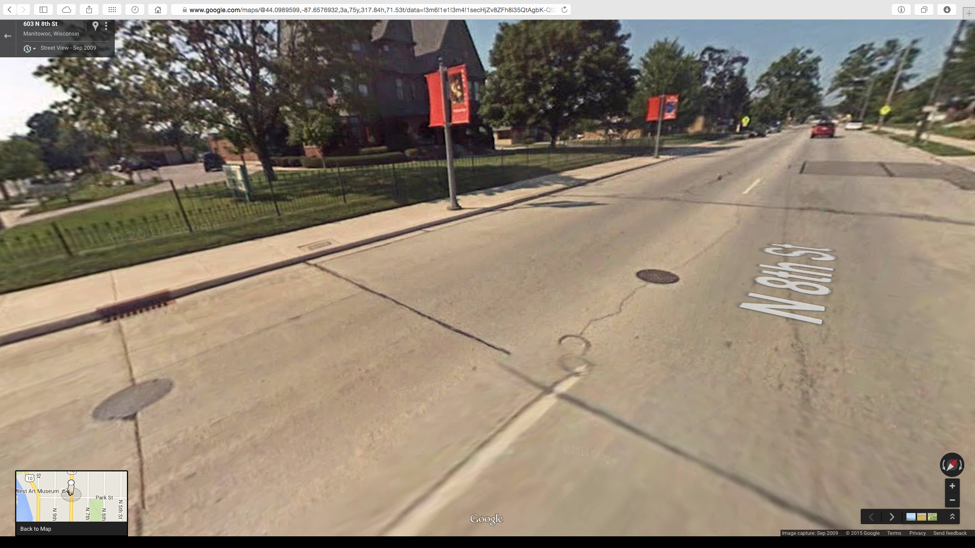 Google Street View image showing the ring in the middle of the road and the pink granite plaque on the sidewalk.